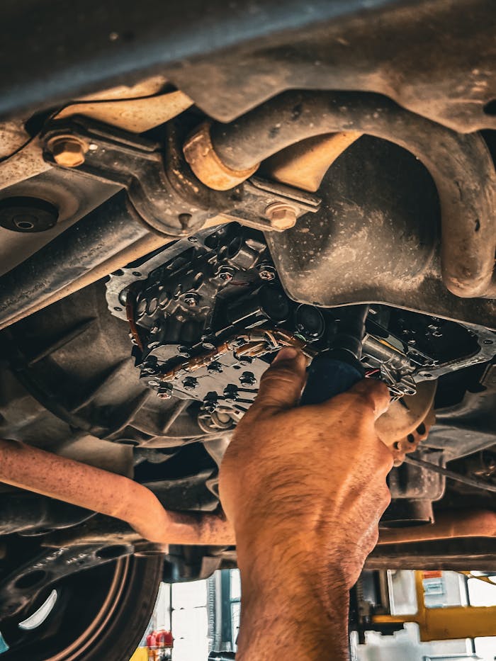 Home Mechanic working on car undercarriage in a garage setting.